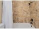 Close-up of a tub-shower combination with textured stone-patterned tile walls at 2855 S Atlantic Ave # 303, Daytona Beach Shores, FL 32118