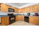 Functional kitchen with wooden cabinets, black appliances, and tile backsplash at 2900 N Atlantic Ave # 2003, Daytona Beach, FL 32118