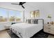 Bright bedroom featuring a ceiling fan, a large window with blinds, and stylish decor with gold accents at 2947 S Atlantic Ave # 201, Daytona Beach Shores, FL 32118