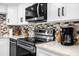 Modern kitchen featuring stainless steel appliances, white cabinetry, stone countertops, and stylish backsplash at 2947 S Atlantic Ave # 201, Daytona Beach Shores, FL 32118