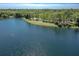 Scenic aerial view of a community lake with shoreline walking path and sunlit reflections on the water at 302 Lamberton Ln, Deland, FL 32724