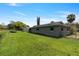 Exterior view of the home with a large backyard, lush grass, mature trees, and partial perimeter fencing at 303 E Floral Ave, Eustis, FL 32726