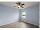 A light blue bedroom with wood-look flooring, a window, and a ceiling fan at 3120 Areca Ave, New Smyrna Beach, FL 32168