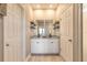 A bathroom featuring a dual sink vanity with decorative shelving, flanked by doors to the water closet and shower at 3128 Crab Trap Dr, New Smyrna Beach, FL 32168