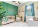 Green Bedroom featuring a stylish crib, accent wall, and comfortable rocking chair at 3128 Crab Trap Dr, New Smyrna Beach, FL 32168