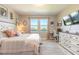 A main bedroom featuring a wall-mounted television, dresser, desk, and two windows with views of the neighborhood pond at 3128 Crab Trap Dr, New Smyrna Beach, FL 32168