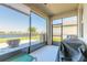 Enclosed patio with serene lake views, a cozy seating area, and a barbecue grill, perfect for relaxation at 3128 Crab Trap Dr, New Smyrna Beach, FL 32168