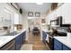 Bright kitchen with white cabinets, blue base cabinets, stainless appliances, modern fixtures, and wood grain floors at 4836 Ne 26Th Ter, Ocala, FL 34479