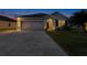 Night shot of a one-story home featuring a two car garage, landscaped yard, and welcoming entryway at 5298 Bear Corn Run, Port Orange, FL 32128