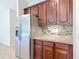 Kitchen with stainless steel fridge, granite countertops, tile backsplash and dark wood cabinets at 669 E Victoria Trails Blvd, Deland, FL 32724
