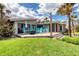 Backyard with a deck featuring colorful Adirondack chairs, palm trees, lush lawn, and ocean views at 787 Ocean Shore Blvd, Ormond Beach, FL 32176