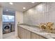 Laundry area features granite countertops, modern backsplash, and front load washer at 787 Ocean Shore Blvd, Ormond Beach, FL 32176