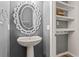 Stylish half-bathroom featuring a pedestal sink, decorative mirror, open shelving and hardwood floors at 8561 Randal Park Blvd, Orlando, FL 32832
