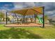 A tan and green playground structure sits under a canopy surrounded by a black fence and green grass at 8561 Randal Park Blvd, Orlando, FL 32832