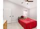 Bedroom with red bedspread, ceiling fan, door and tile floors, showing its functional layout at 999 Trumbull St, Deltona, FL 32725