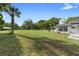 An expansive, grassy backyard featuring mature trees and the house, with a clear blue sky above at 1560 S Pearl St, Deland, FL 32720