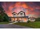 Striking two-story modern farmhouse at sunset, featuring a welcoming front porch and manicured lawn at 1015 Tallacoe Trl, New Smyrna Beach, FL 32168