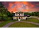 Stunning farmhouse-style home with a welcoming front porch and picturesque sunset sky at 1015 Tallacoe Trl, New Smyrna Beach, FL 32168