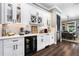 Elegant kitchen bar area with white cabinetry, wine storage, a built-in beverage cooler, and quartz countertops at 1015 Tallacoe Trl, New Smyrna Beach, FL 32168