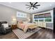 Comfortable main bedroom with neutral tones, wood floors, a ceiling fan, and windows providing scenic outdoor views at 1015 Tallacoe Trl, New Smyrna Beach, FL 32168