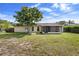 View of the backyard featuring a mature tree, screened in porch, and grassy lawn at 1054 Abeline Dr, Deltona, FL 32725