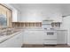 Bright kitchen featuring white cabinets, appliances, modern laminate flooring, and double sinks at 1054 Abeline Dr, Deltona, FL 32725