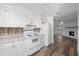 Bright white kitchen with white appliances and view into the living room with fireplace at 1054 Abeline Dr, Deltona, FL 32725