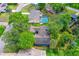 Overhead shot of a property featuring a charming blue home with mature trees, a pool, and lush green surroundings at 1206 Parkside Dr, Ormond Beach, FL 32174