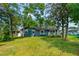 Lush backyard featuring mature trees, a well-kept lawn, and a charming blue house, ideal for relaxation and recreation at 1206 Parkside Dr, Ormond Beach, FL 32174