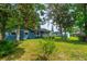 Spacious backyard with lush greenery, mature trees, and a charming blue home, offering privacy and tranquility at 1206 Parkside Dr, Ormond Beach, FL 32174