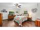 Comfortable bedroom with hardwood floors, ceiling fan, two windows, and a colorful bedspread at 1206 Parkside Dr, Ormond Beach, FL 32174