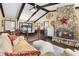 Open concept living room with a stone fireplace, wood beams, and an adjacent dining area, perfect for entertaining at 1206 Parkside Dr, Ormond Beach, FL 32174