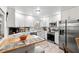 Modern kitchen featuring white cabinets, stainless steel appliances, marble countertops, and an adjacent breakfast bar at 135 Moonstone Ct, Port Orange, FL 32129