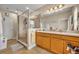 Bathroom featuring dual sinks, a glass-enclosed shower, and neutral tile flooring at 1436 Lobelia Dr, Lake Mary, FL 32746