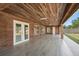 Expansive covered patio with wood plank ceiling, red brick walls and gray wood-look tile flooring at 1440 Portola Ave, Deltona, FL 32738