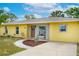 Close-up of the front of the yellow house showing brick detail, a bench, and a beautifully landscaped walkway at 1511 Jack St, Tavares, FL 32778