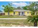 Charming yellow home featuring a well-manicured lawn and welcoming front entrance with bench and plants at 1511 Jack St, Tavares, FL 32778