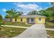 Lovely yellow house with a long driveway and walkway leading to the front door and a beautifully kept lawn at 1511 Jack St, Tavares, FL 32778