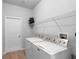 Bright laundry room featuring a white washer and dryer set with upper shelf and wood-look flooring at 1601 Toledo Ave, Deltona, FL 32725