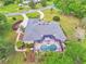 Aerial view of a home with screened-in pool, lush landscaping and outdoor patio at 1661 Timber Hills Dr, Deland, FL 32724