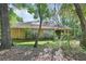 Backyard showcasing a brick home with solar panels nestled among mature trees at 1925 Hamilton Ave, Orange City, FL 32763