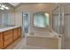 Bathroom with a vanity, soaking tub, shower, and frosted window for privacy at 1925 Hamilton Ave, Orange City, FL 32763