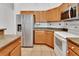 Functional kitchen with wood cabinets, stainless steel refrigerator, and white appliances at 1925 Hamilton Ave, Orange City, FL 32763
