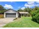 Charming single-story home with a well-manicured lawn, gray siding, and a two-car garage at 219 Brevity Ln, Deland, FL 32724