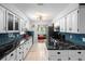 Bright kitchen featuring white cabinets, blue backsplash, black marble countertops, and stainless steel appliances at 219 Brevity Ln, Deland, FL 32724