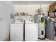 Bright laundry room featuring a washing machine, dryer, water heater and shelving space for organizing supplies at 219 Brevity Ln, Deland, FL 32724