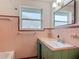Bathroom featuring vintage-style pink tile, updated vanity, sink, mirror, and window at 243 S Hull Ave, Deland, FL 32720