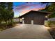 Charming home showcasing a two-car garage, dark exterior paint, and a spacious driveway, enhanced by a colorful sunset backdrop at 265 S Fairbairn Dr, Deltona, FL 32725