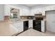 A kitchen with white cabinets, a double sink, a black dishwasher, and a black glass top oven at 265 S Fairbairn Dr, Deltona, FL 32725