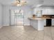 A modern kitchen featuring white cabinets, a breakfast bar, and seamless transition to a cozy sunroom at 265 S Fairbairn Dr, Deltona, FL 32725
